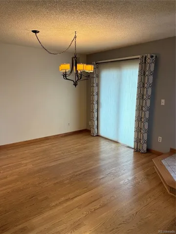 an empty room with wooden floor mirror and windows