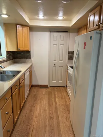 a view of a kitchen with a sink and dishwasher with wooden floor