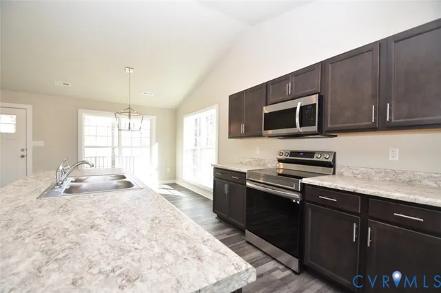 a kitchen with stainless steel appliances granite countertop a stove a sink and a microwave