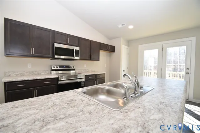 a kitchen with granite countertop a sink stainless steel appliances and cabinets