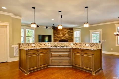 a kitchen with kitchen island granite countertop a stove a sink a center island and a wooden floor
