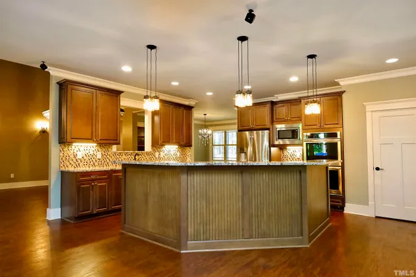 a large kitchen with granite countertop a stove a sink a refrigerator and a wooden floor