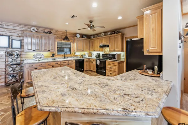 a kitchen with stainless steel appliances kitchen island granite countertop a sink stove and refrigerator