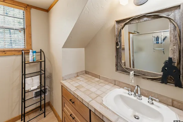 a bathroom with a granite countertop shower sink and mirror
