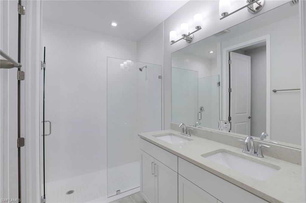 7473 Rockefeller Drive Naples, FL 34119 - Photo 11 of 19 a bathroom with double sink and a mirror