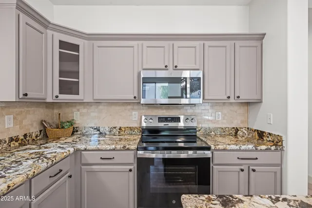 a kitchen with stainless steel appliances granite countertop a stove and a white cabinets
