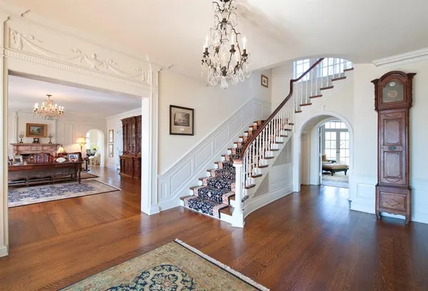 a view of a hallway with wooden floor staircase and a living room