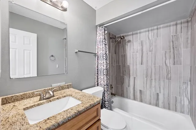 a bathroom with a granite countertop sink toilet and shower