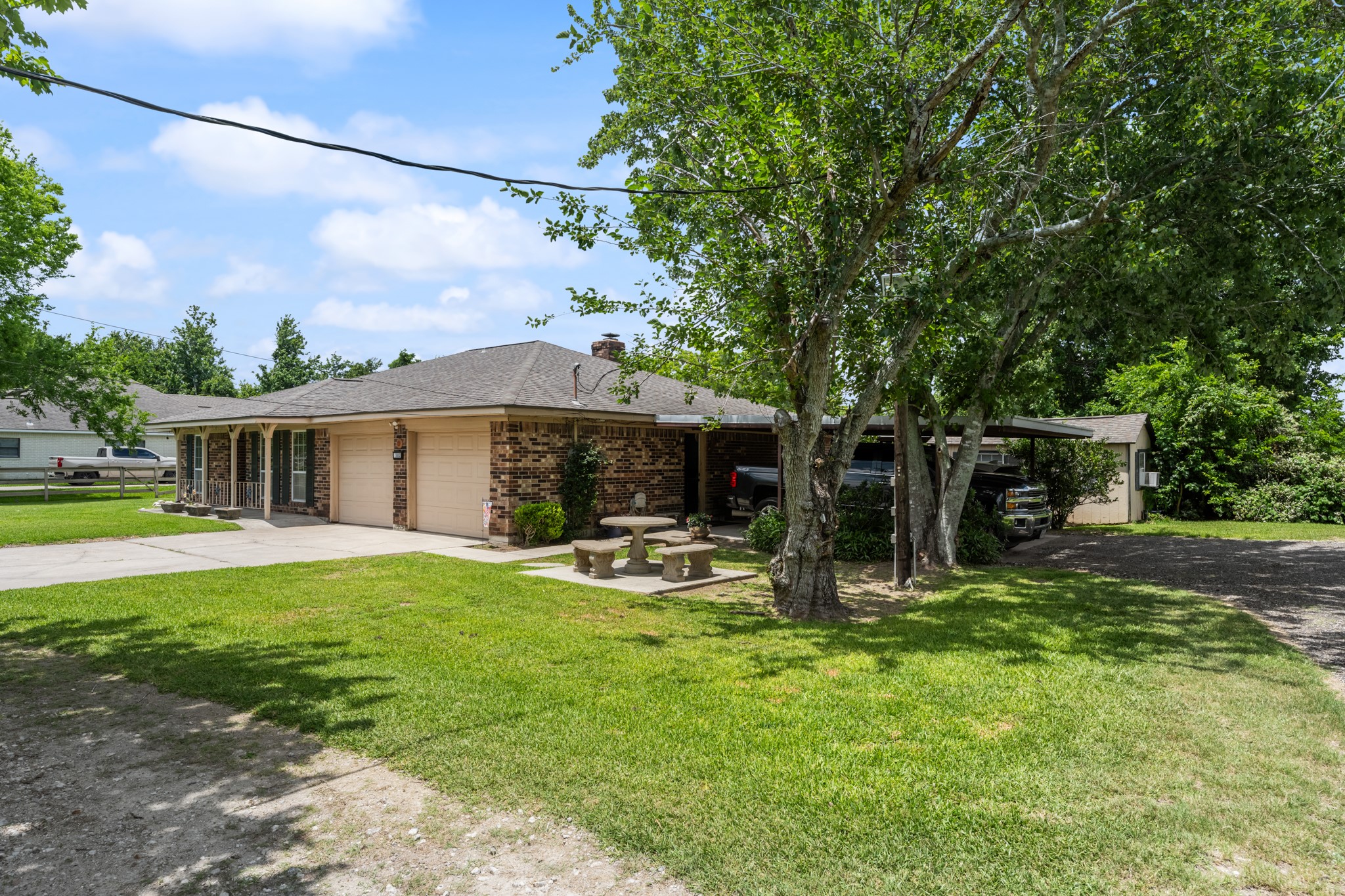 15602 Fir Road Santa Fe, TX 77517 - Photo 39 of 42 Charming brick exterior with mature shade trees, a spacious driveway, attached garage, and covered parking for added convenience. The expansive front lawn and country-style setting create a welcoming first impression.