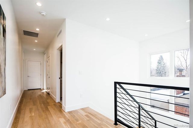 a view of a hallway with wooden floor and a bathroom