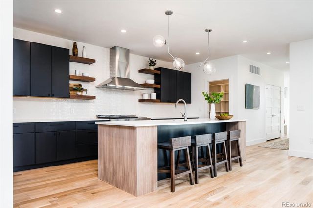 a kitchen with stainless steel appliances kitchen island granite countertop a stove a sink and a refrigerator