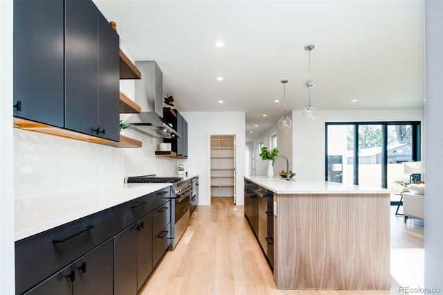 a kitchen with stainless steel appliances granite countertop a refrigerator a sink dishwasher a oven and a dining table with wooden floor