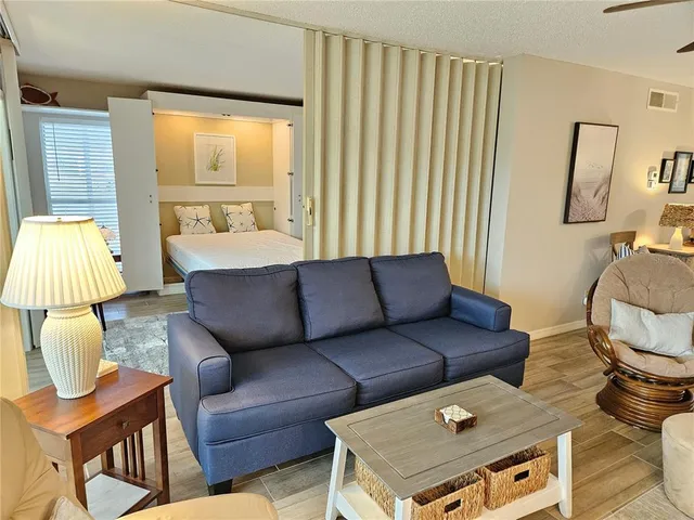 a living room with furniture and a dining table with wooden floor