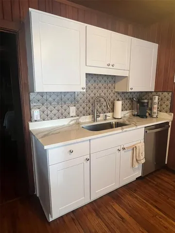 a kitchen with granite countertop a sink cabinets and stainless steel appliances