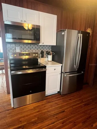 a kitchen with cabinets wooden floor and stainless steel appliances