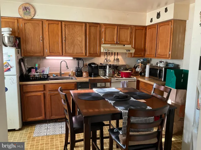 a kitchen with stainless steel appliances granite countertop a table chairs sink and cabinets