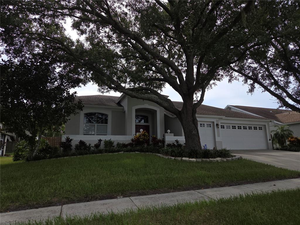 a front view of a house with a garden and trees