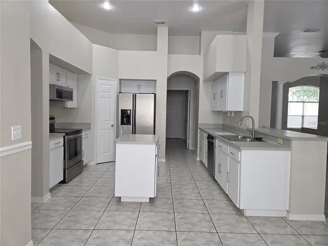a large kitchen with stainless steel appliances a refrigerator and a stove top oven