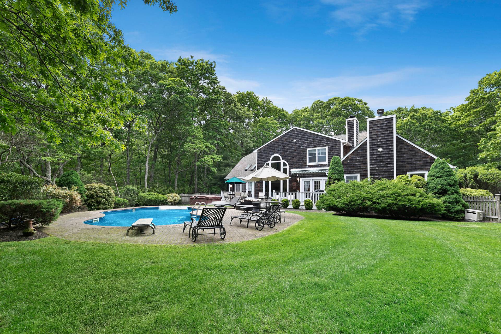 a backyard of a house with table and chairs plants and large tree