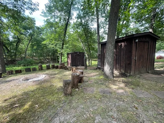 a view of a backyard with large trees and wooden fence