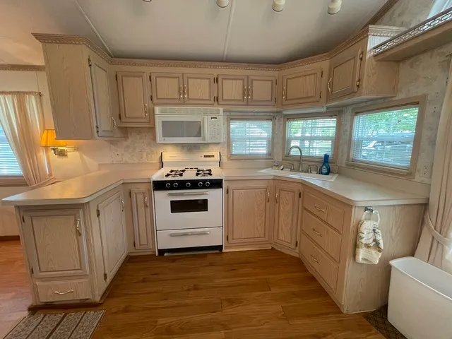 a kitchen with granite countertop a sink cabinets stainless steel appliances and a window