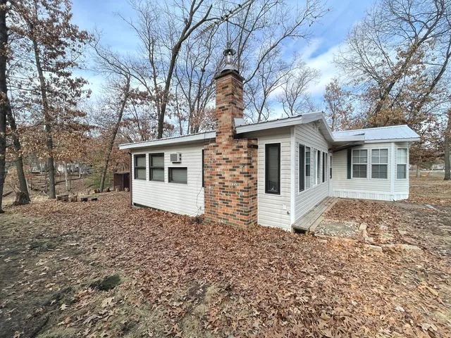 a view of a house with a large tree and wooden fence
