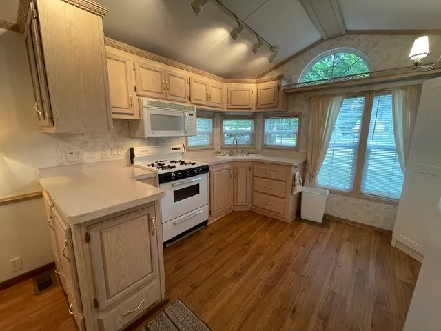 a kitchen with granite countertop wooden floors and white stainless steel appliances