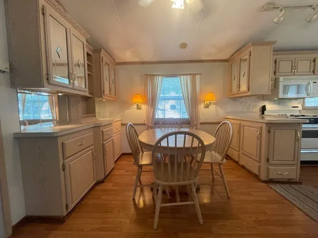 a kitchen with stainless steel appliances granite countertop a table chairs sink and cabinets