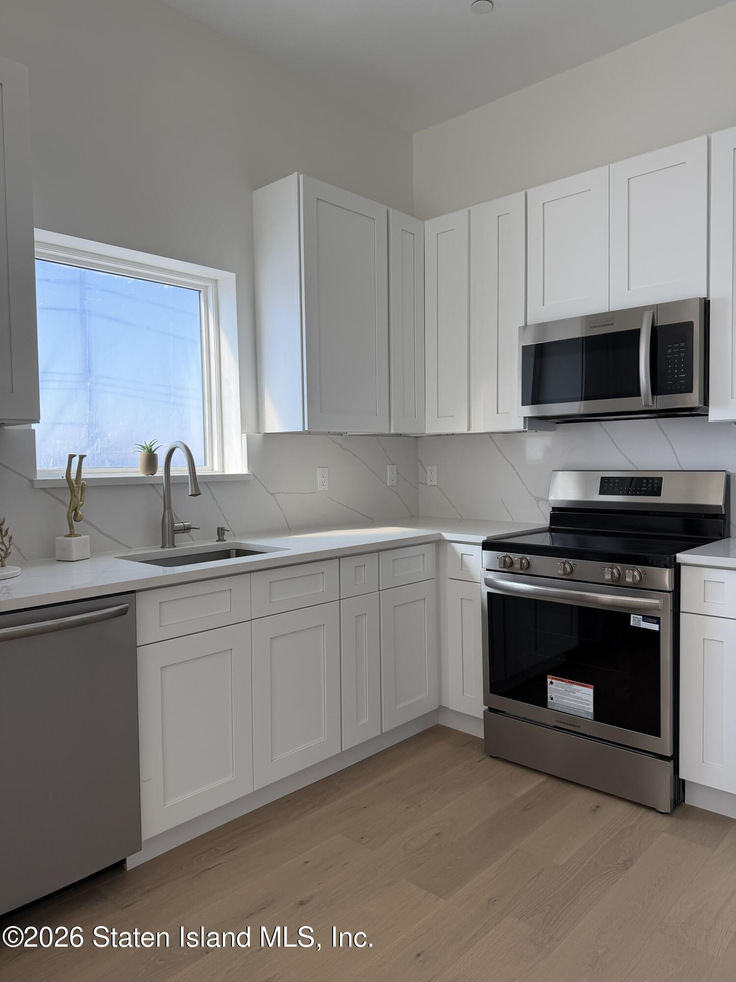 1239 Forest Hill Road, Unit 24 Staten Island, NY 10314 - Photo 4 of 8 a kitchen with stainless steel appliances granite countertop a stove microwave and sink