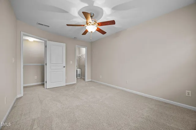 an empty room with closet and a ceiling fan