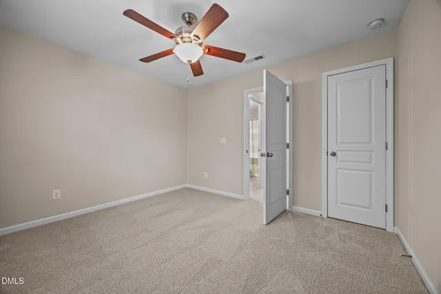 an empty room with closet and a ceiling fan