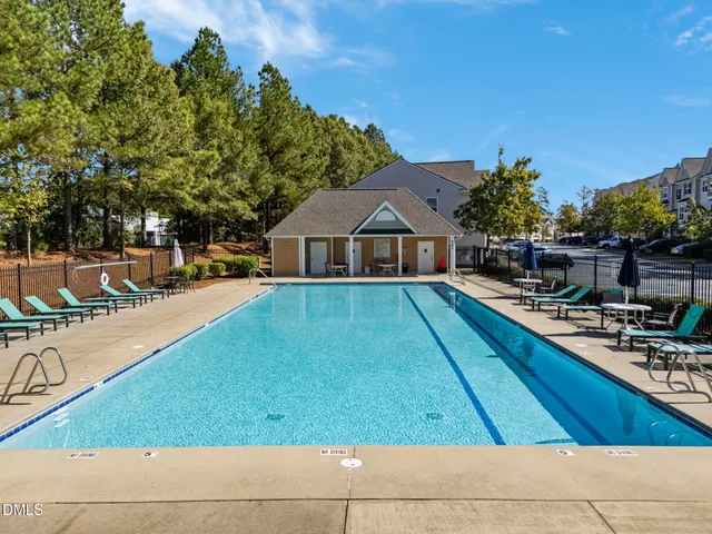 a view of swimming pool with lounge chair and dinning table under an umbrella