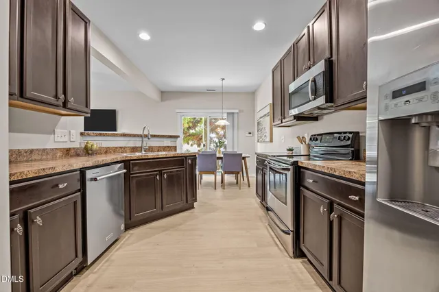 a kitchen with stainless steel appliances granite countertop a stove top oven a sink dishwasher a refrigerator and cabinets with wooden floor