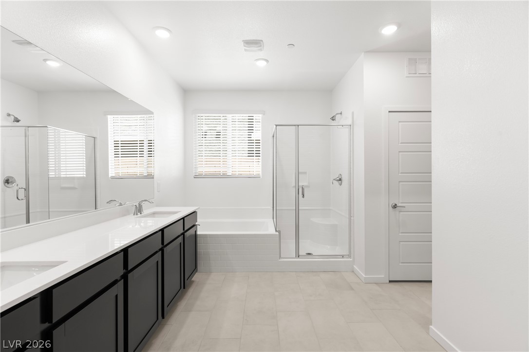 320 Isla Enclave Way Henderson, NV 89011 - Photo 13 of 49 A well-appointed bathroom features a long double vanity, a tub, and a separate glass-enclosed shower.