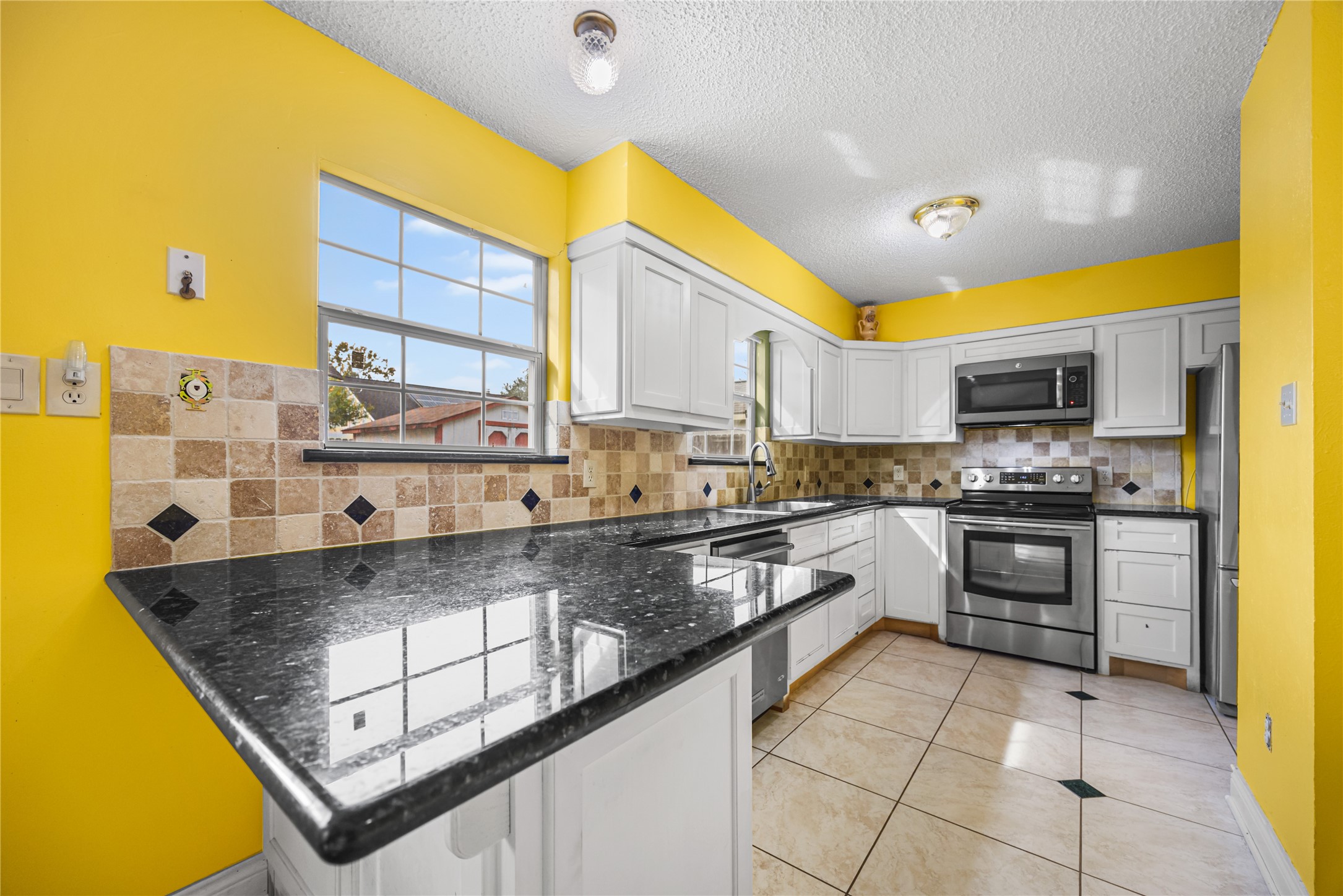 7211 Sandswept Lane Houston, TX 77086 - Photo 19 of 29 a kitchen with stainless steel appliances granite countertop a stove a sink and a microwave