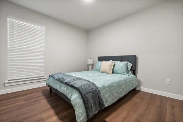 a bed sitting in a bedroom next to a window and a wooden floor