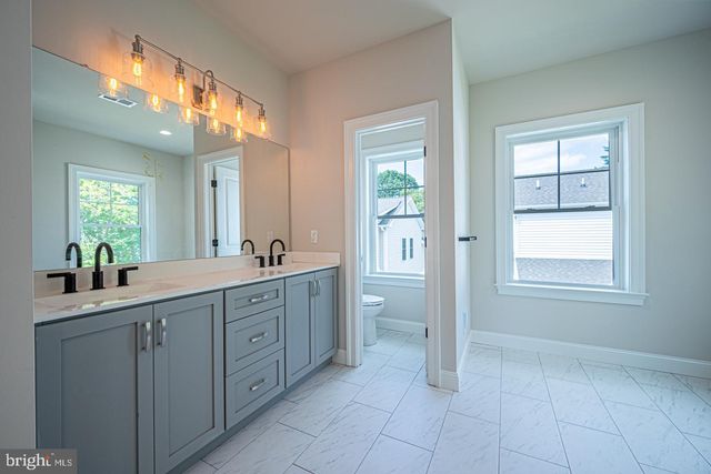 a spacious bathroom with a granite countertop sink a toilet and a mirror