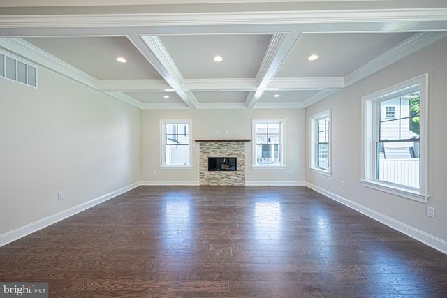 an empty room with wooden floor fireplace and windows