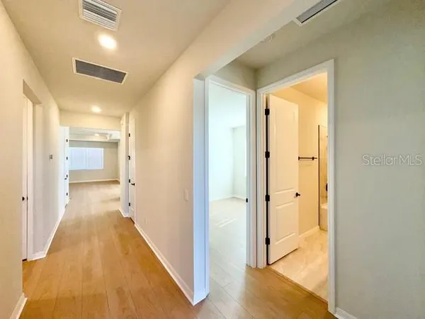 a view of a hallway with wooden floor and a bathroom