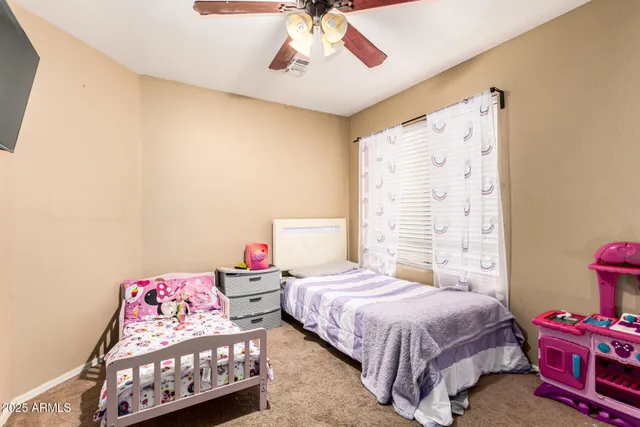 a bedroom with a bed a dresser and a chandelier