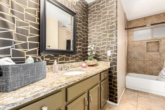 a bathroom with a granite countertop sink a mirror and a bathtub