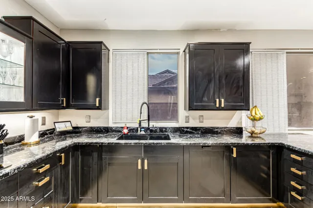 a kitchen with granite countertop a sink a stove and cabinets