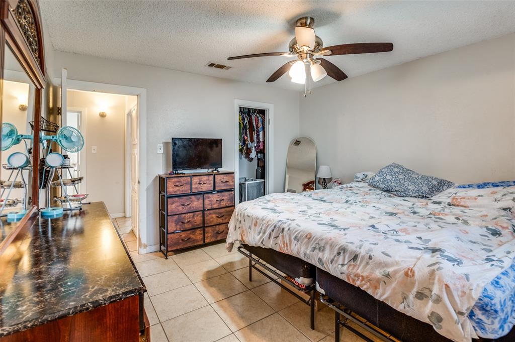 6102 Kelly Elliott Road Arlington, TX 76001 - Photo 10 of 12 a bedroom with a bed and a flat tv screen on a dresser