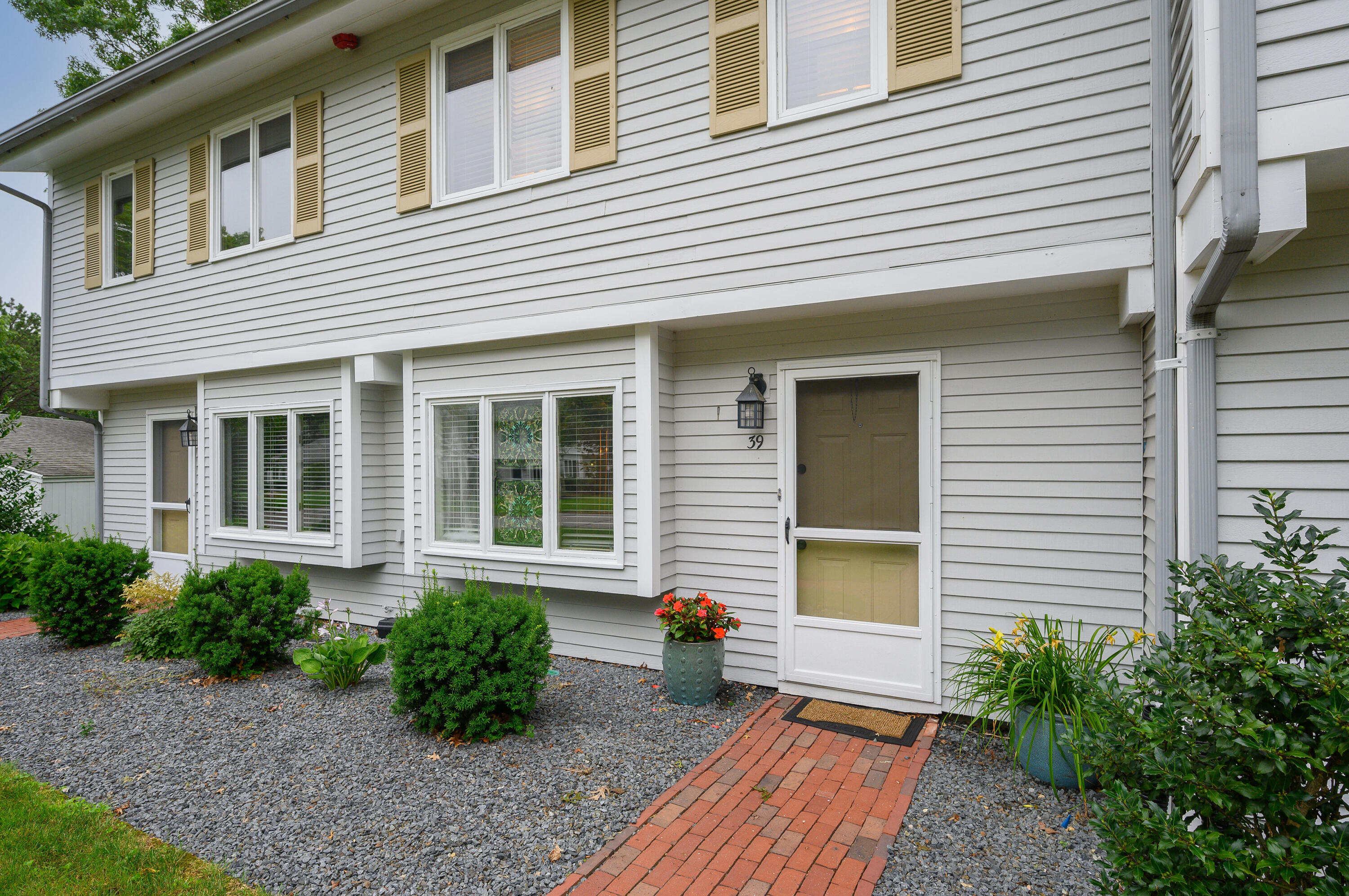 a view of brick house with potted plants in front of door