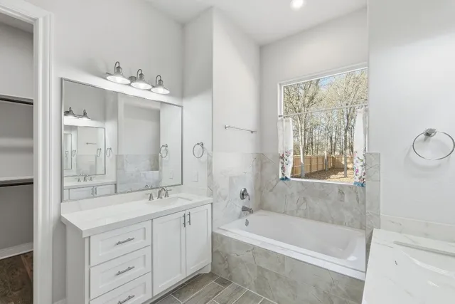a bathroom with a double vanity sink bathtub and next to a window