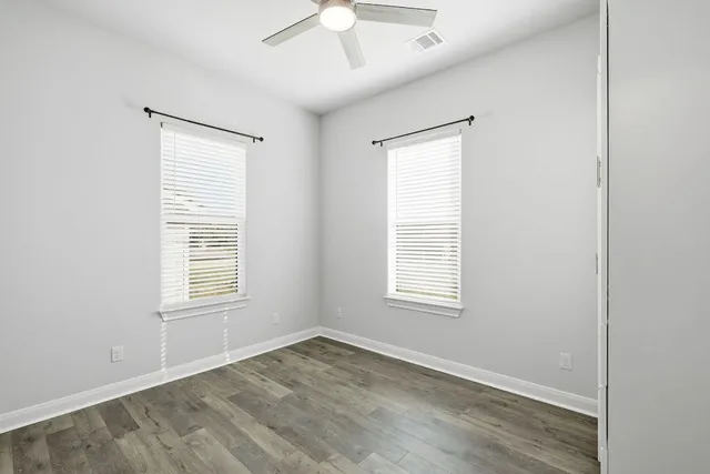 an empty room with wooden floor and windows