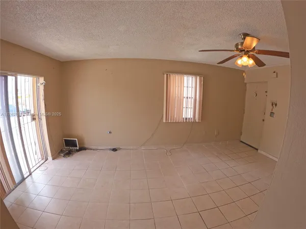 an empty room with windows and chandelier fan