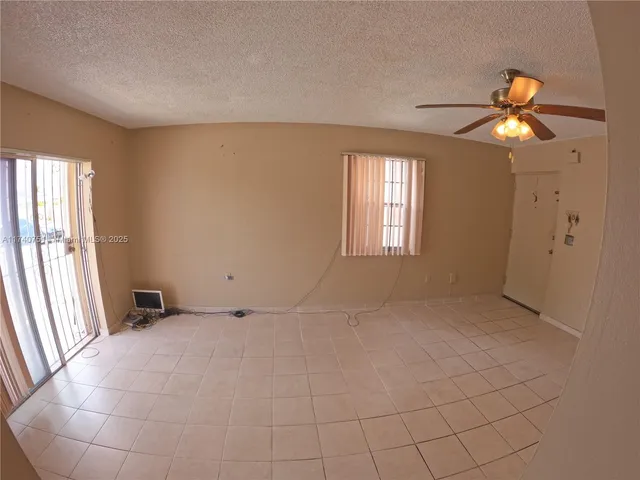an empty room with windows and chandelier fan
