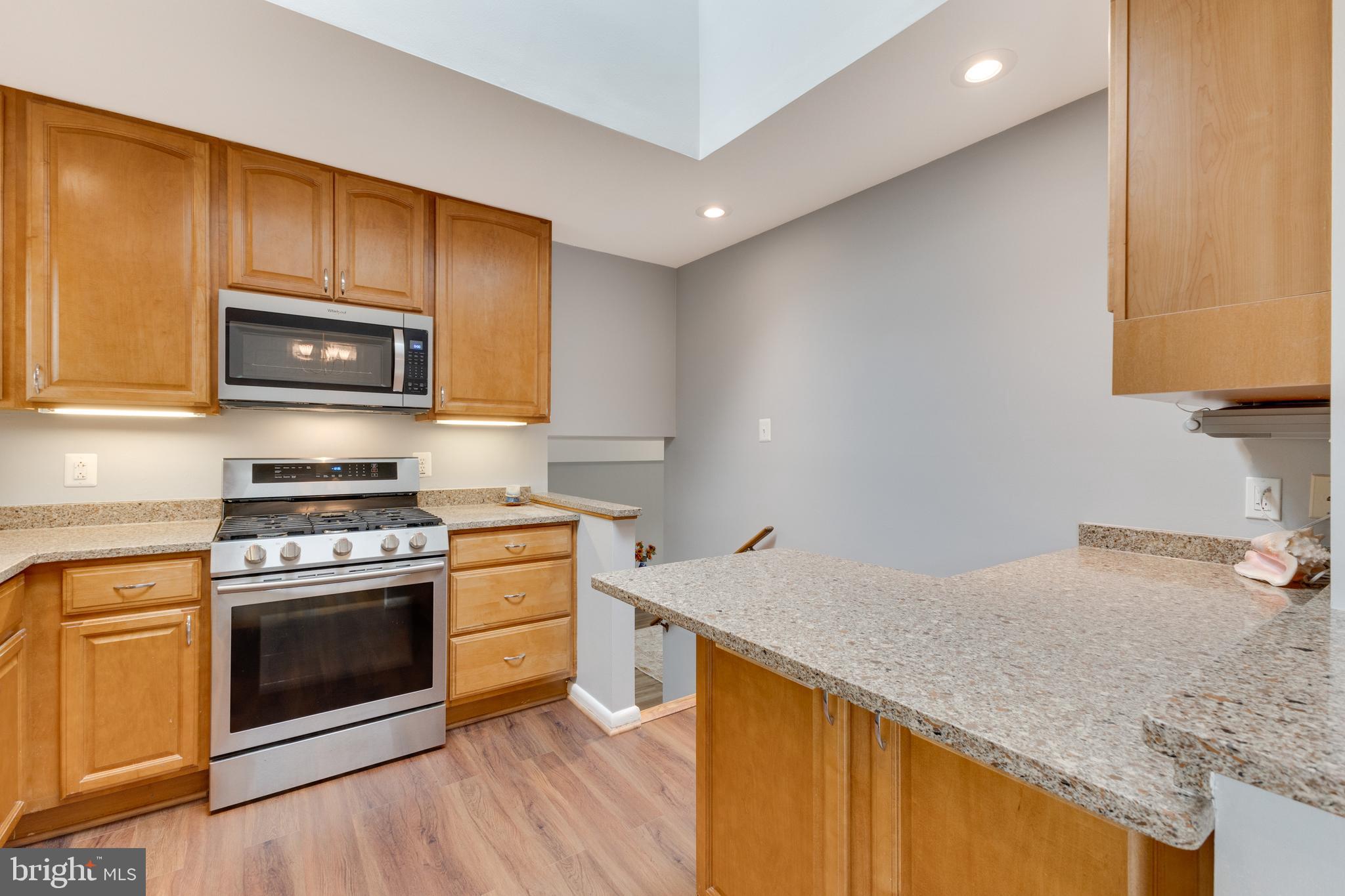 8816 Battery Road Alexandria, VA 22308 - Photo 12 of 25 a kitchen with granite countertop wooden cabinets stove and microwave
