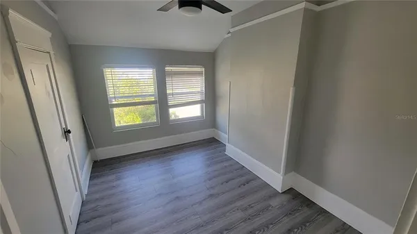 an empty room with wooden floor and windows